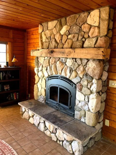 Rustic stone fireplace with wooden mantel in cozy interior